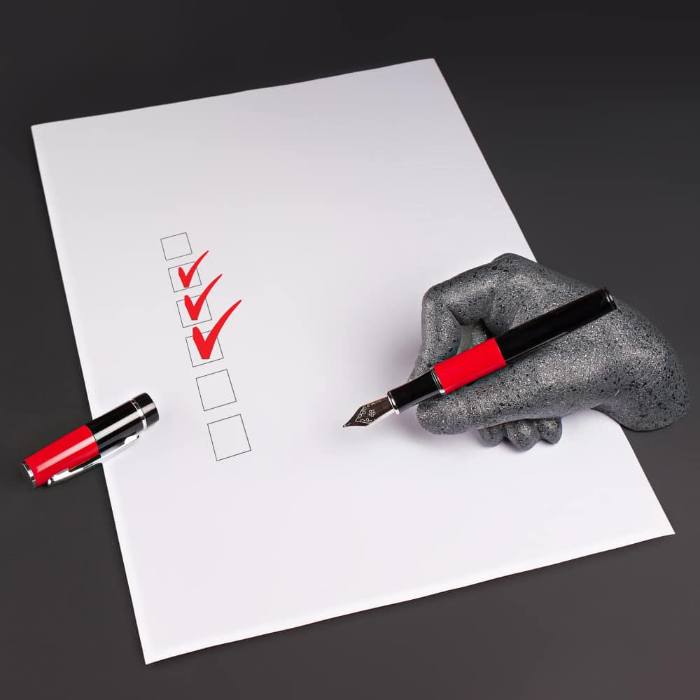 يد تمسك قلم على ورقة بها علامات حمراء يد تمسك قلم على ورقة بها علامات حمراء