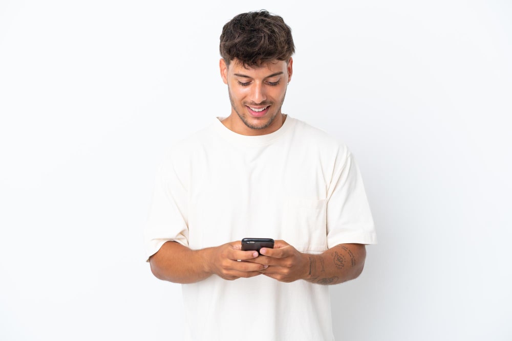 شاب ينظر إلى الهاتف المحمول وهو مبتسم