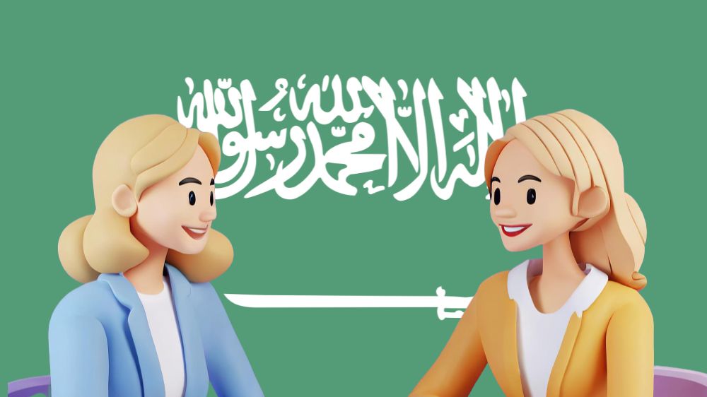 فتاتان يجلسان أمام العلم السعودي