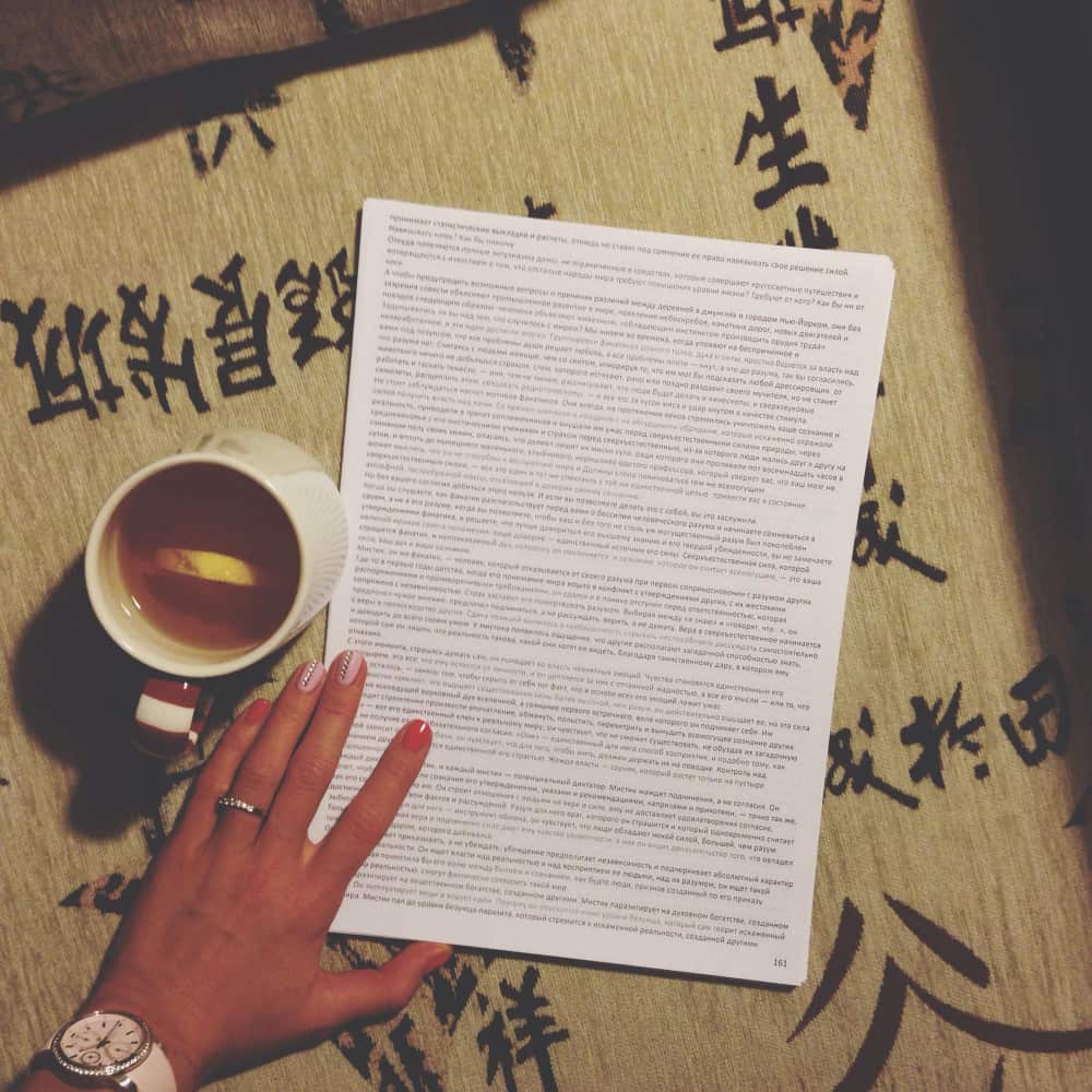 يد تمسك ورقة وبجانبها كوب من الشاي