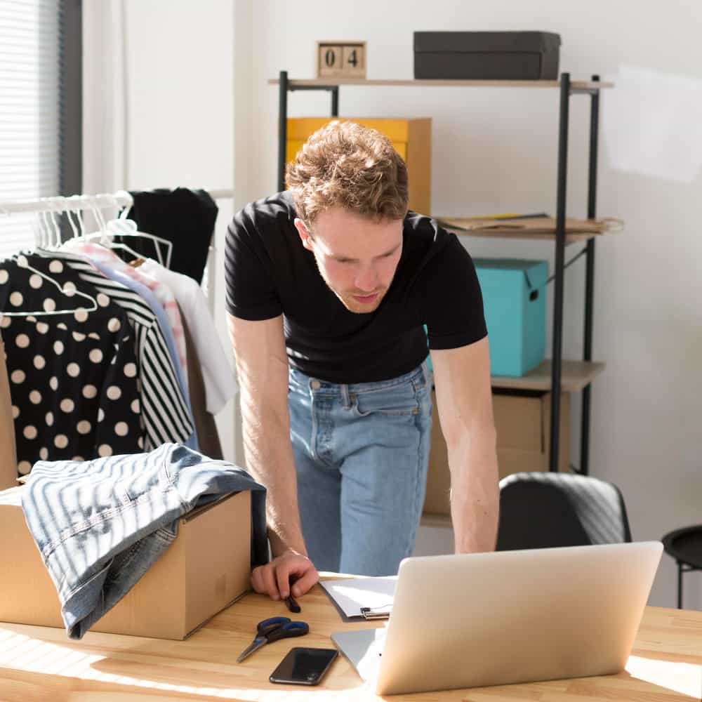 رجل في متجر ملابس وينظر إلى شاشة لاب توب