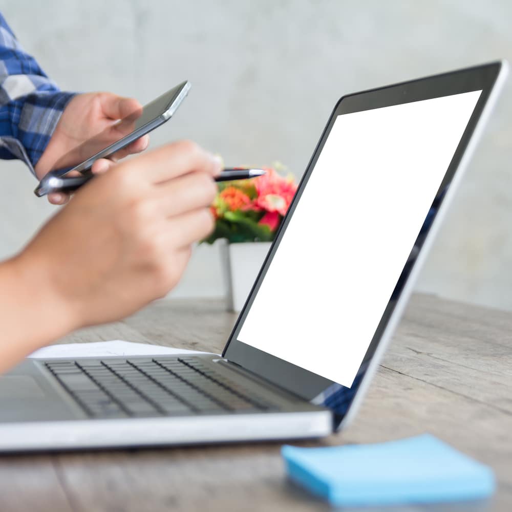 يد تحمل قلم وتشير إلى لاب توب