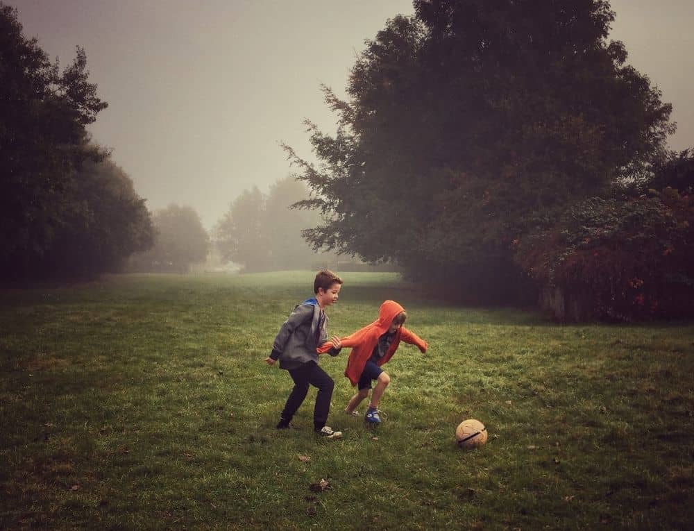 ولدان يلعبان بالكرة في حديقة