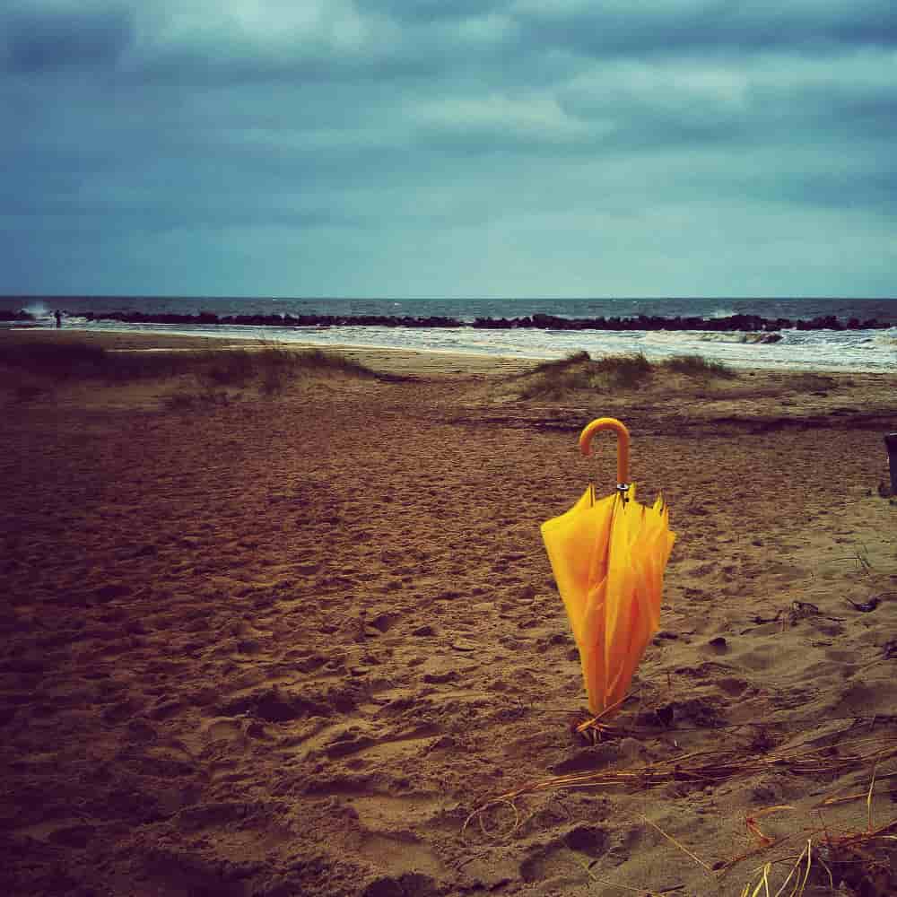 مظلة صفراء على الرمل بجانب الشاطئ