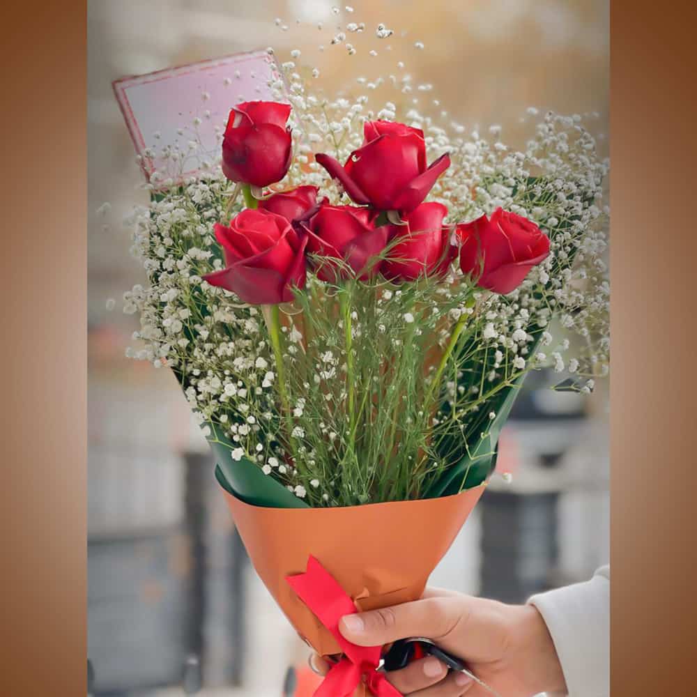 يد تحمل باقة زهور حمراء يد تحمل باقة زهور حمراء